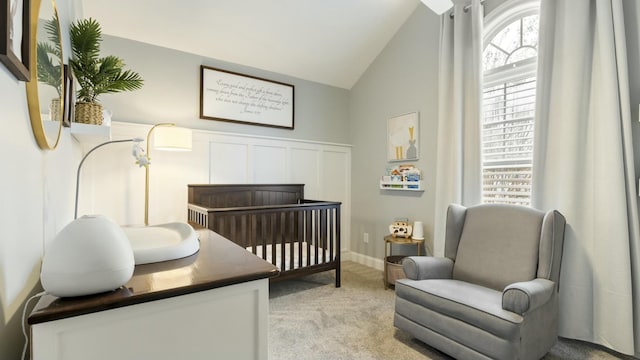 bedroom with lofted ceiling, light carpet, and a crib