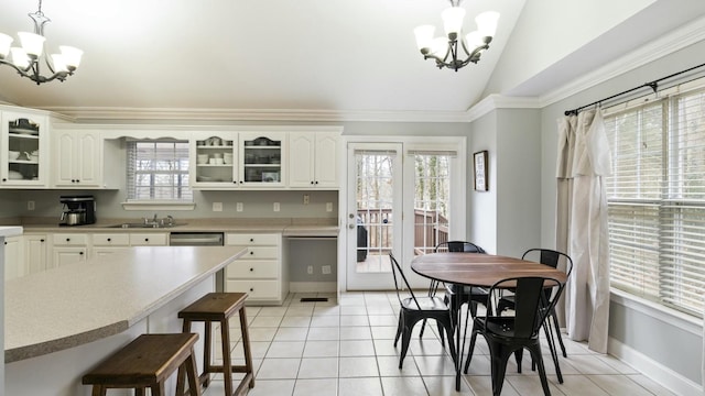 kitchen featuring hanging light fixtures, white cabinets, light tile patterned flooring, an inviting chandelier, and lofted ceiling