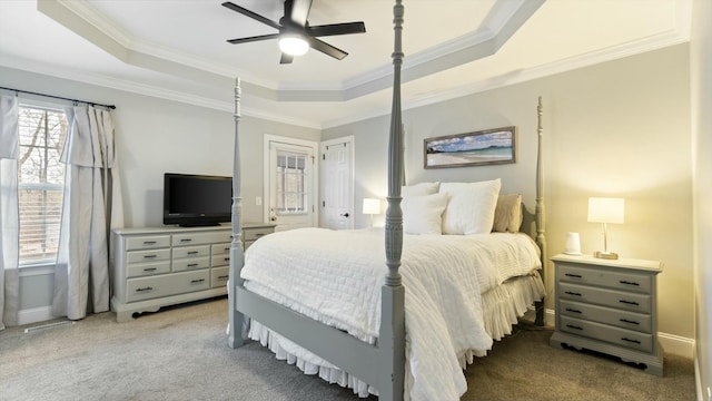 carpeted bedroom with ceiling fan, a tray ceiling, and ornamental molding