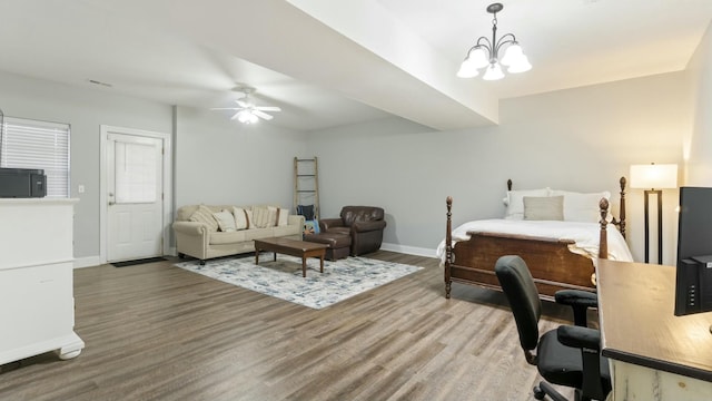 bedroom featuring ceiling fan with notable chandelier and wood-type flooring