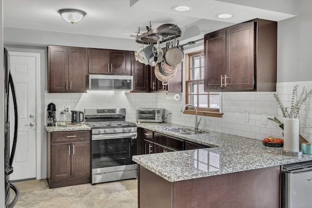 kitchen featuring light stone countertops, sink, backsplash, and stainless steel appliances