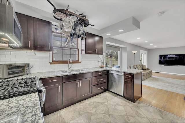 kitchen with light stone countertops, sink, appliances with stainless steel finishes, and light hardwood / wood-style flooring