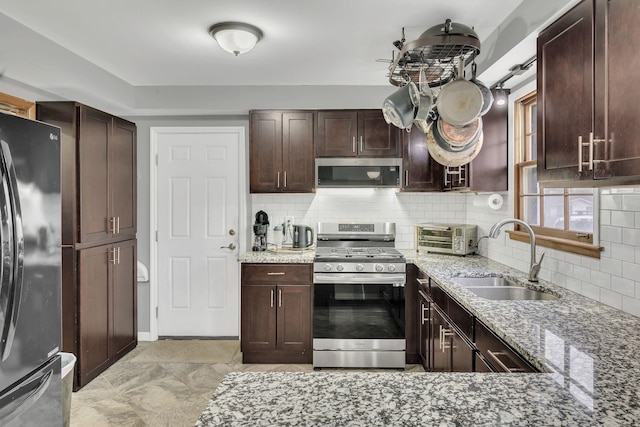 kitchen with light stone counters, sink, and appliances with stainless steel finishes