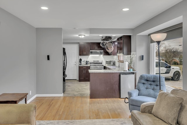 kitchen featuring dark brown cabinets, sink, light wood-type flooring, decorative backsplash, and stainless steel appliances