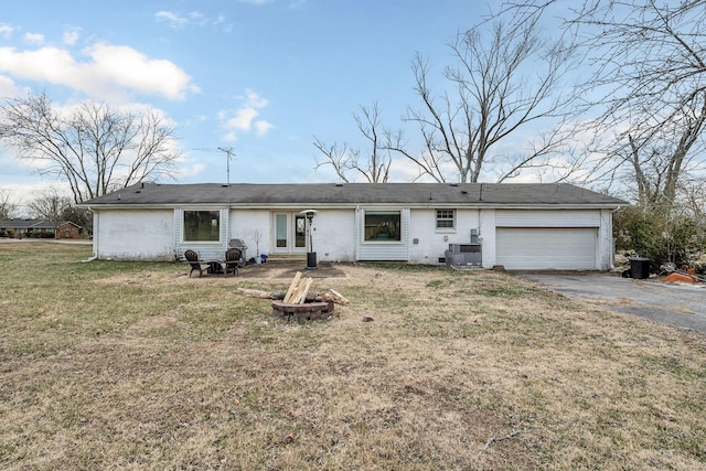 single story home featuring an outdoor fire pit, cooling unit, a front yard, and a garage