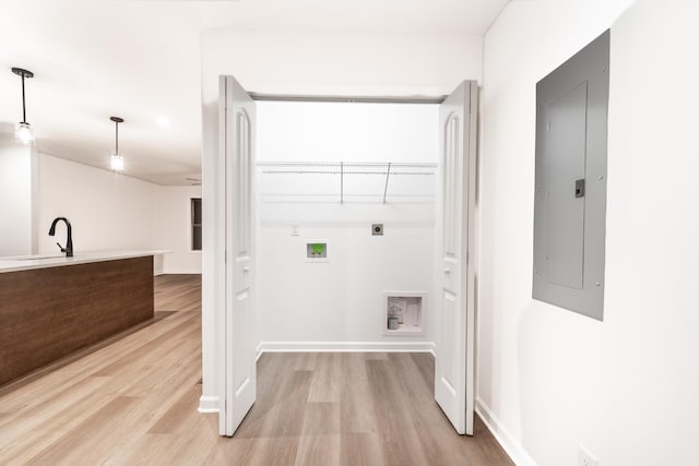 washroom with hookup for an electric dryer, a sink, light wood-type flooring, laundry area, and electric panel