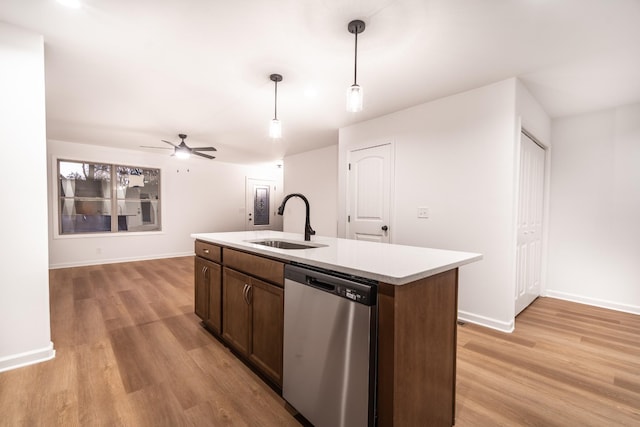 kitchen featuring a sink, light wood-style floors, light countertops, dishwasher, and decorative light fixtures