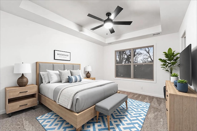 bedroom featuring dark colored carpet, a raised ceiling, visible vents, a ceiling fan, and baseboards