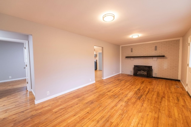 unfurnished living room featuring a brick fireplace and light hardwood / wood-style flooring