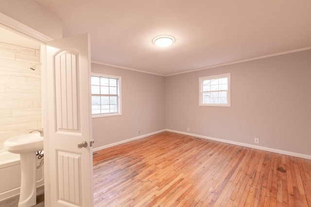 unfurnished room featuring crown molding, plenty of natural light, and light hardwood / wood-style flooring