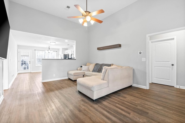 living room with ceiling fan with notable chandelier, high vaulted ceiling, and dark hardwood / wood-style floors