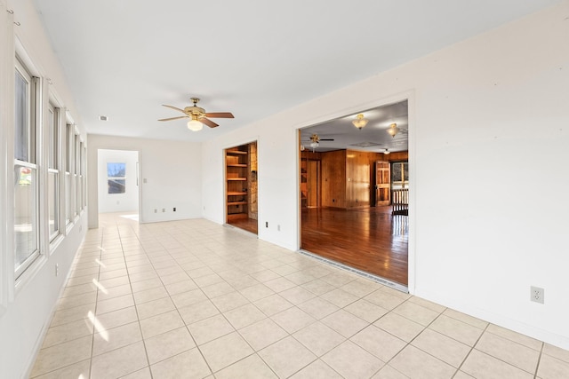 spare room featuring ceiling fan, light tile patterned floors, and wooden walls