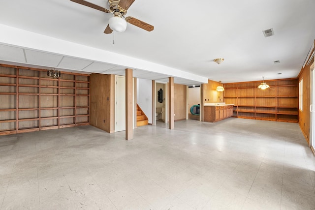 basement featuring ceiling fan and wood walls