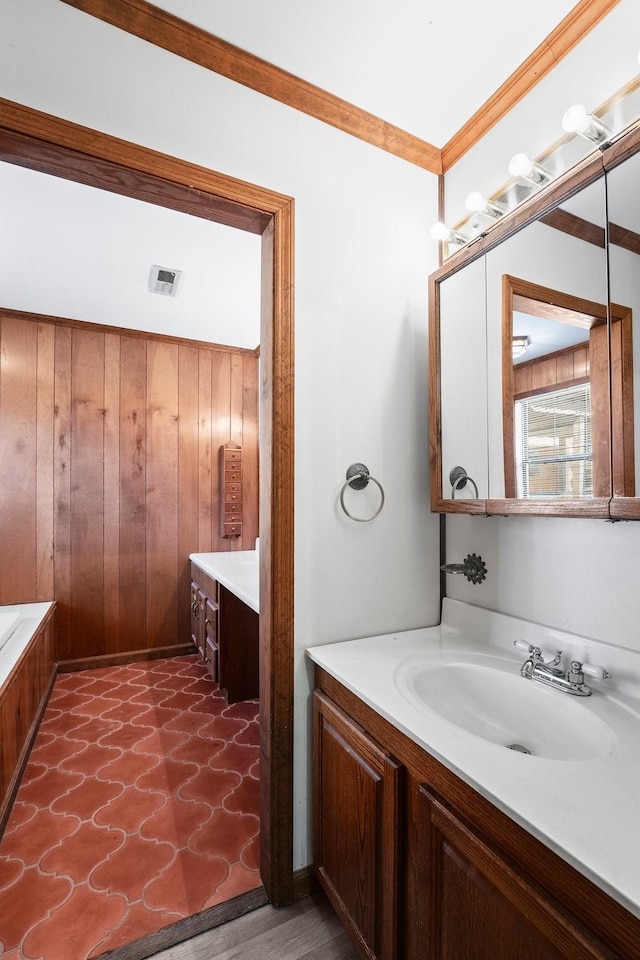 bathroom featuring crown molding, vanity, and wooden walls