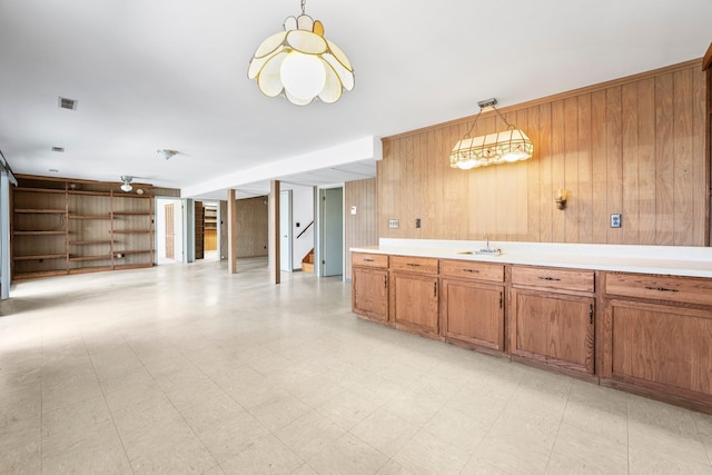 kitchen featuring hanging light fixtures, sink, and wood walls