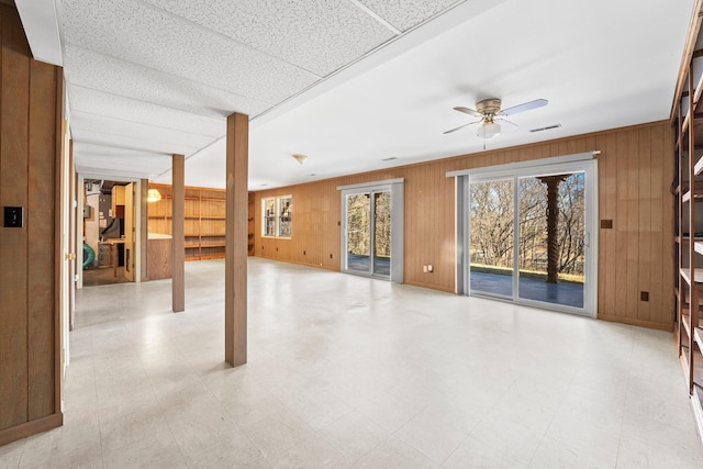 interior space featuring ceiling fan and wooden walls