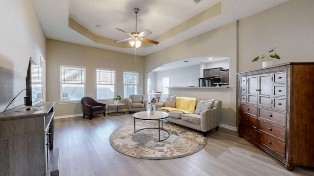 living room featuring ceiling fan, a raised ceiling, and light hardwood / wood-style floors