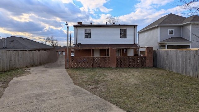 back of property with covered porch and a yard