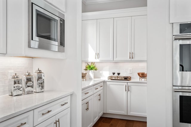 kitchen with stainless steel appliances, light stone countertops, dark wood-type flooring, and white cabinets