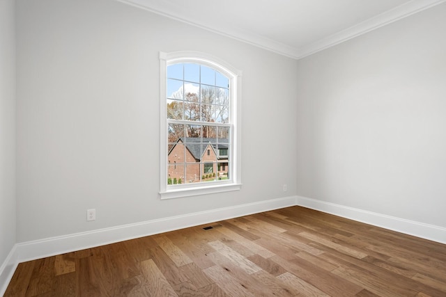 spare room with ornamental molding, plenty of natural light, and light hardwood / wood-style floors