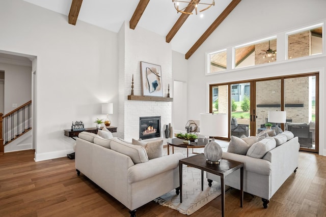 living room with a brick fireplace, beam ceiling, dark wood-type flooring, and a high ceiling