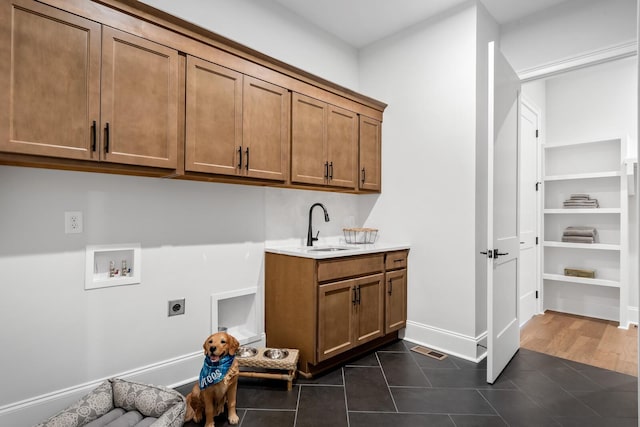 laundry room with sink, cabinets, dark tile patterned floors, washer hookup, and hookup for an electric dryer