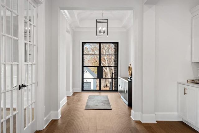 doorway featuring hardwood / wood-style flooring, ornamental molding, and a notable chandelier