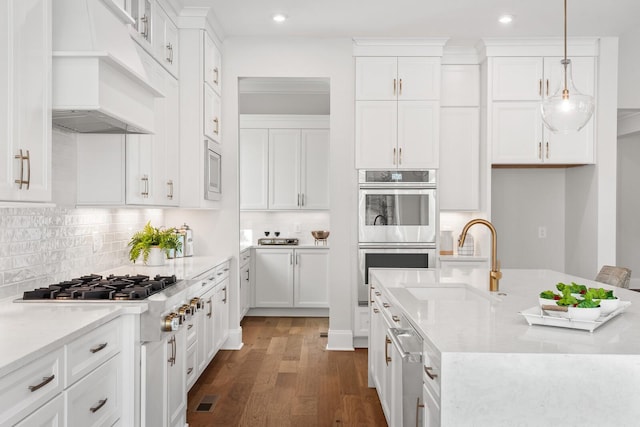 kitchen with sink, decorative light fixtures, appliances with stainless steel finishes, light stone countertops, and white cabinets