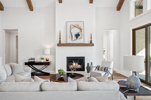 living room featuring beamed ceiling, hardwood / wood-style flooring, and a fireplace