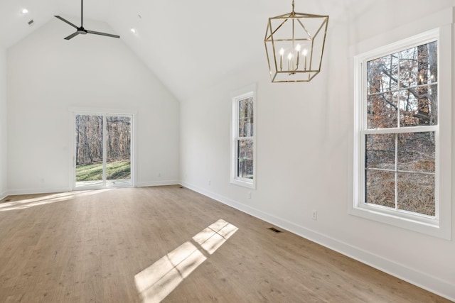 unfurnished dining area with wood-type flooring, vaulted ceiling, and ceiling fan with notable chandelier