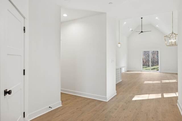 corridor featuring an inviting chandelier, vaulted ceiling, and light hardwood / wood-style flooring