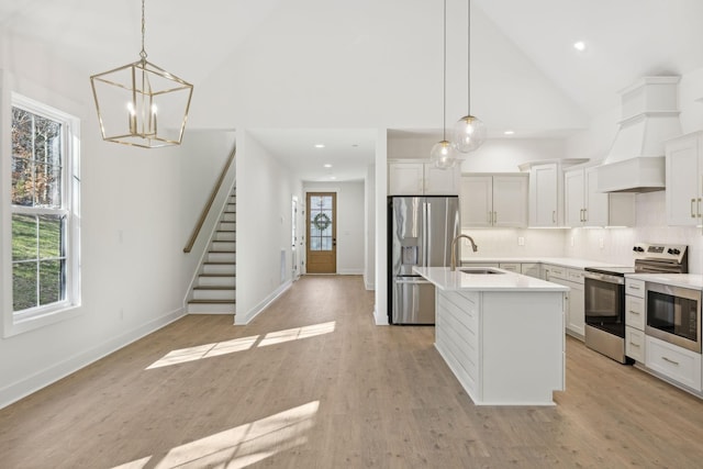 kitchen featuring appliances with stainless steel finishes, decorative light fixtures, tasteful backsplash, an island with sink, and sink