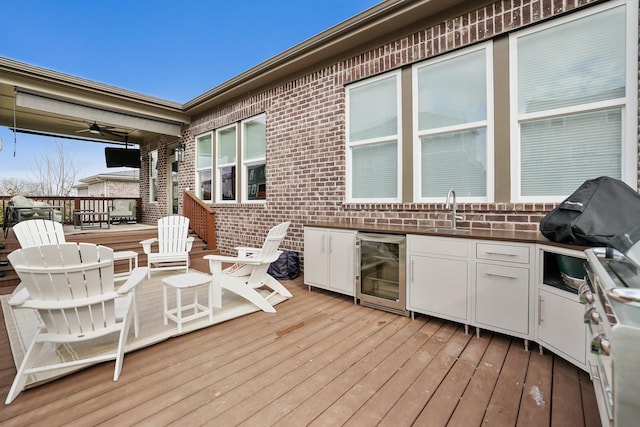 wooden terrace featuring ceiling fan, sink, beverage cooler, and area for grilling