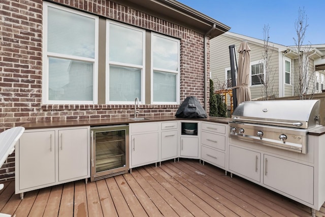 deck with sink, an outdoor kitchen, beverage cooler, and a grill