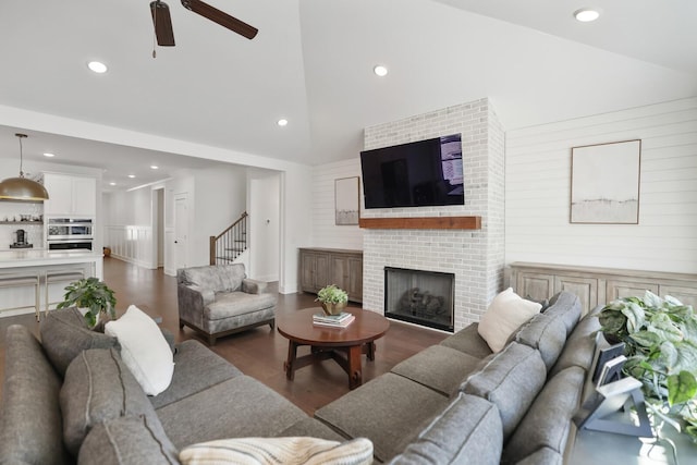 living room with ceiling fan, dark hardwood / wood-style flooring, lofted ceiling, and a fireplace