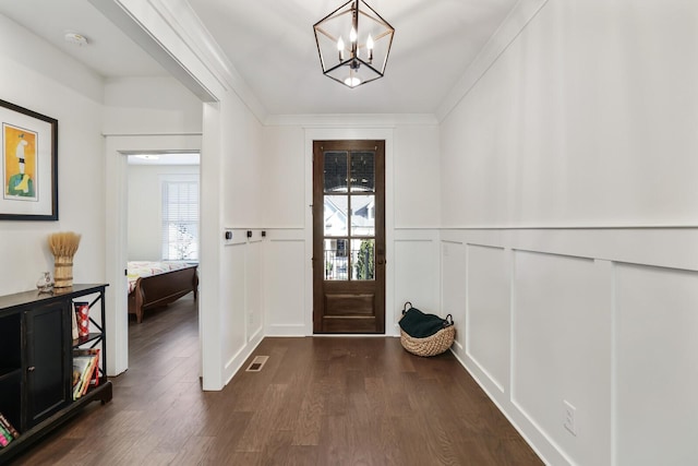 foyer with a chandelier, ornamental molding, and dark hardwood / wood-style floors