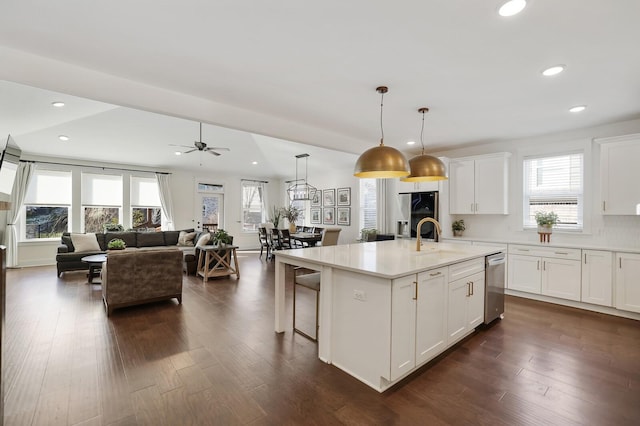 kitchen featuring a kitchen bar, white cabinetry, pendant lighting, an island with sink, and dark hardwood / wood-style floors