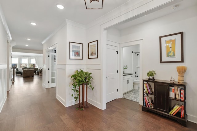 hallway with ornamental molding and dark wood-type flooring