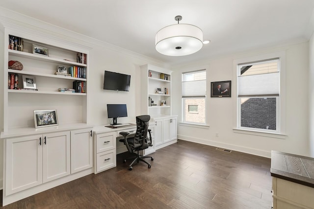 office area with built in shelves, ornamental molding, dark wood-type flooring, and built in desk