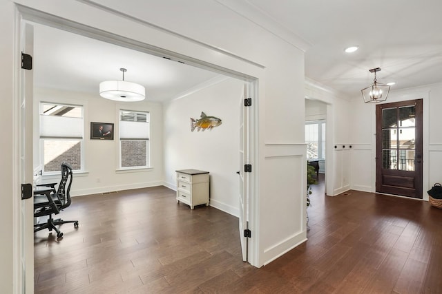 foyer entrance with crown molding, dark wood-type flooring, and an inviting chandelier