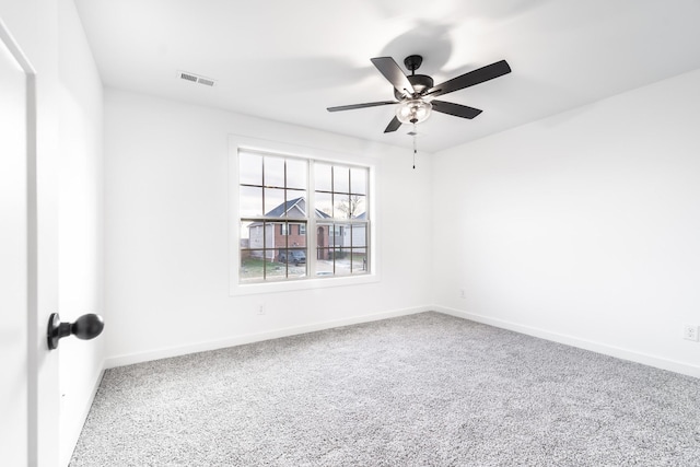 carpeted empty room featuring baseboards, visible vents, and a ceiling fan