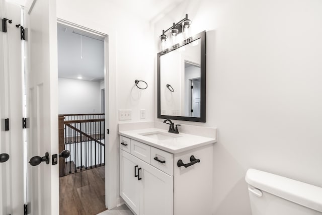 bathroom featuring toilet, wood finished floors, and vanity