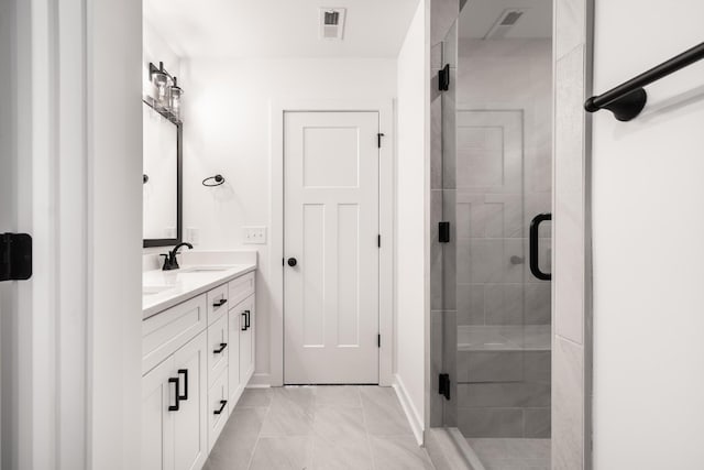 full bath with double vanity, a shower stall, visible vents, and a sink