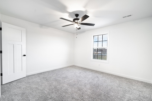 unfurnished room featuring carpet floors, visible vents, baseboards, and a ceiling fan