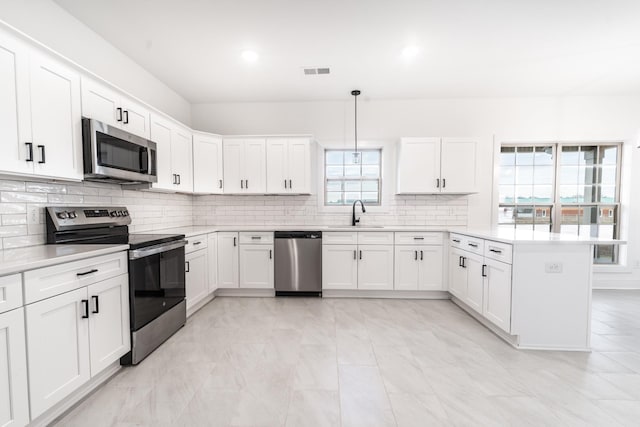 kitchen with tasteful backsplash, visible vents, a peninsula, stainless steel appliances, and light countertops