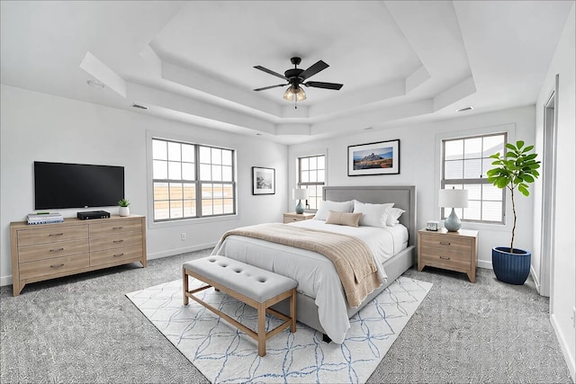 bedroom with light carpet, baseboards, visible vents, and a raised ceiling