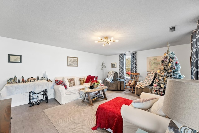 living room featuring hardwood / wood-style flooring, a textured ceiling, and a notable chandelier