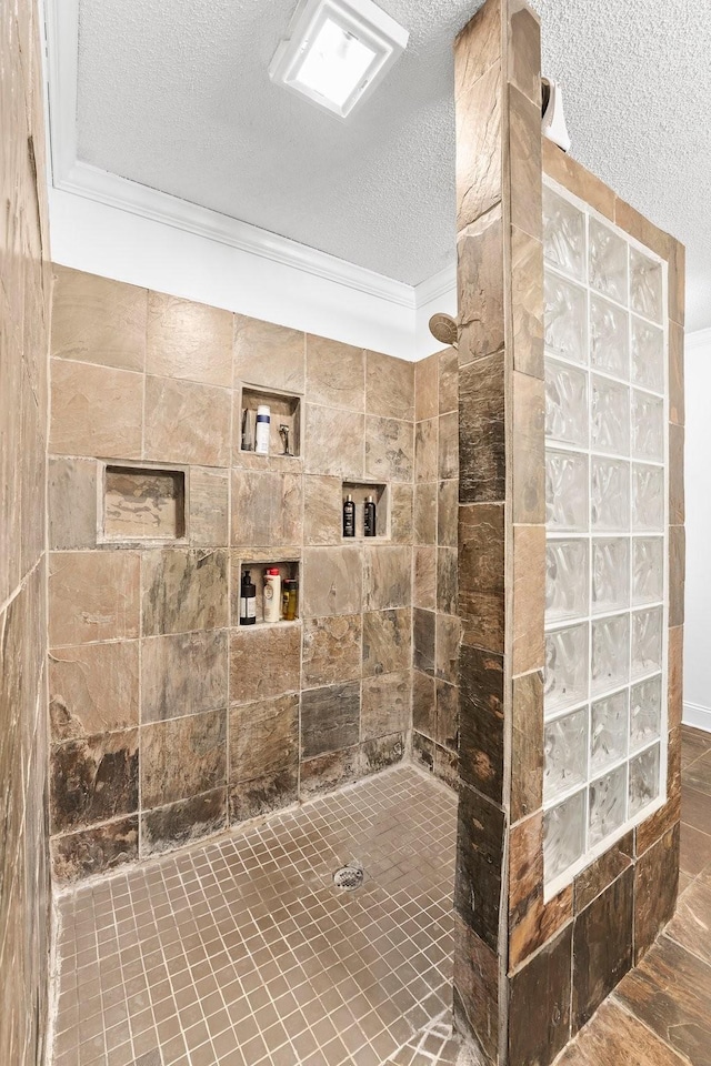 bathroom with ornamental molding, tiled shower, and a textured ceiling