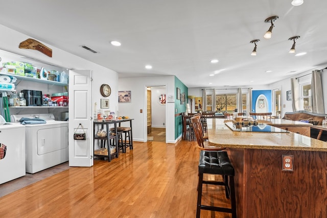 kitchen featuring light stone counters, washing machine and dryer, and light wood-type flooring