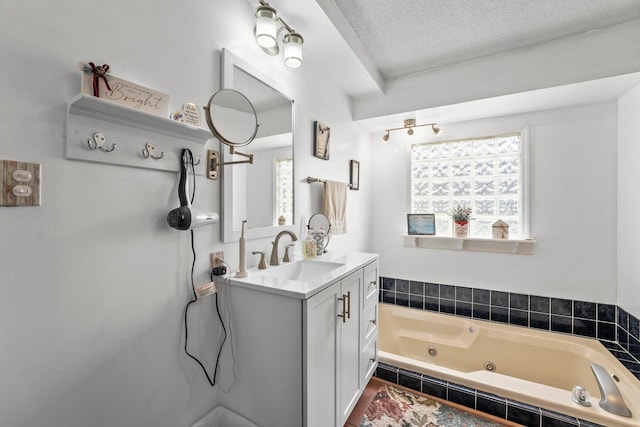 bathroom featuring vanity, tiled bath, and a textured ceiling